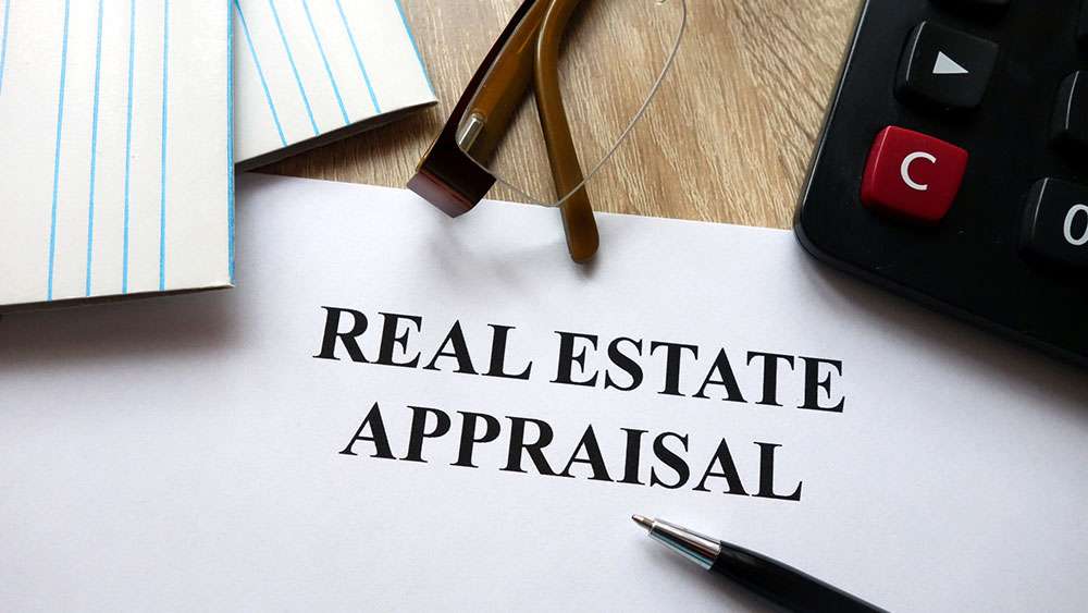 Real estate appraisal document with pen, calculator, and glasses on desk